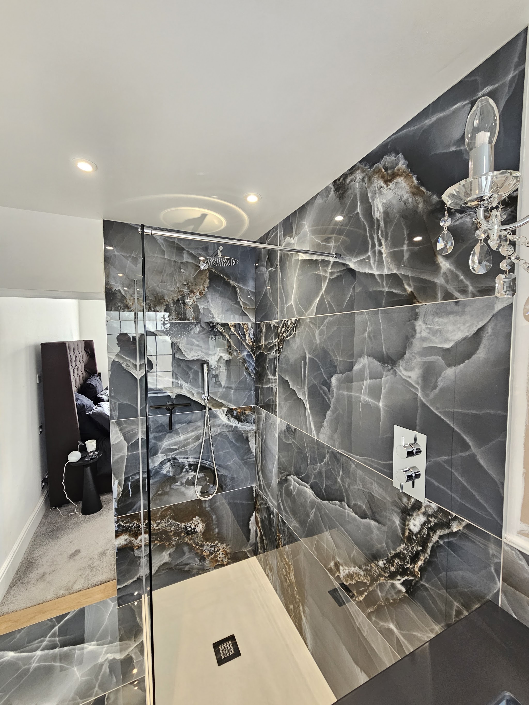 Walk-in shower lined with dark marble-effect tiles
