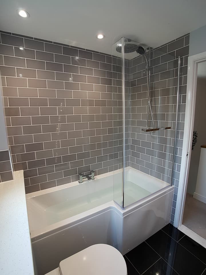 Shower bath with grey metro tiles and a black floor