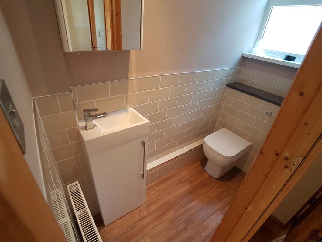 Compact cloakroom basin unit and WC on a wood-effect floor