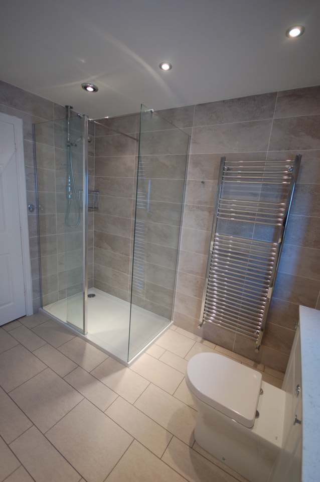 Walk-in shower and chrome towel rail in a tiled bathroom