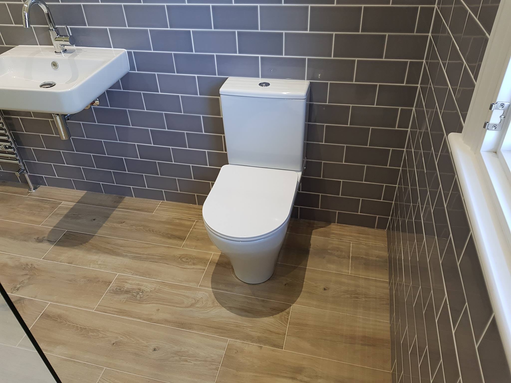 Close-coupled WC beside grey metro tiles